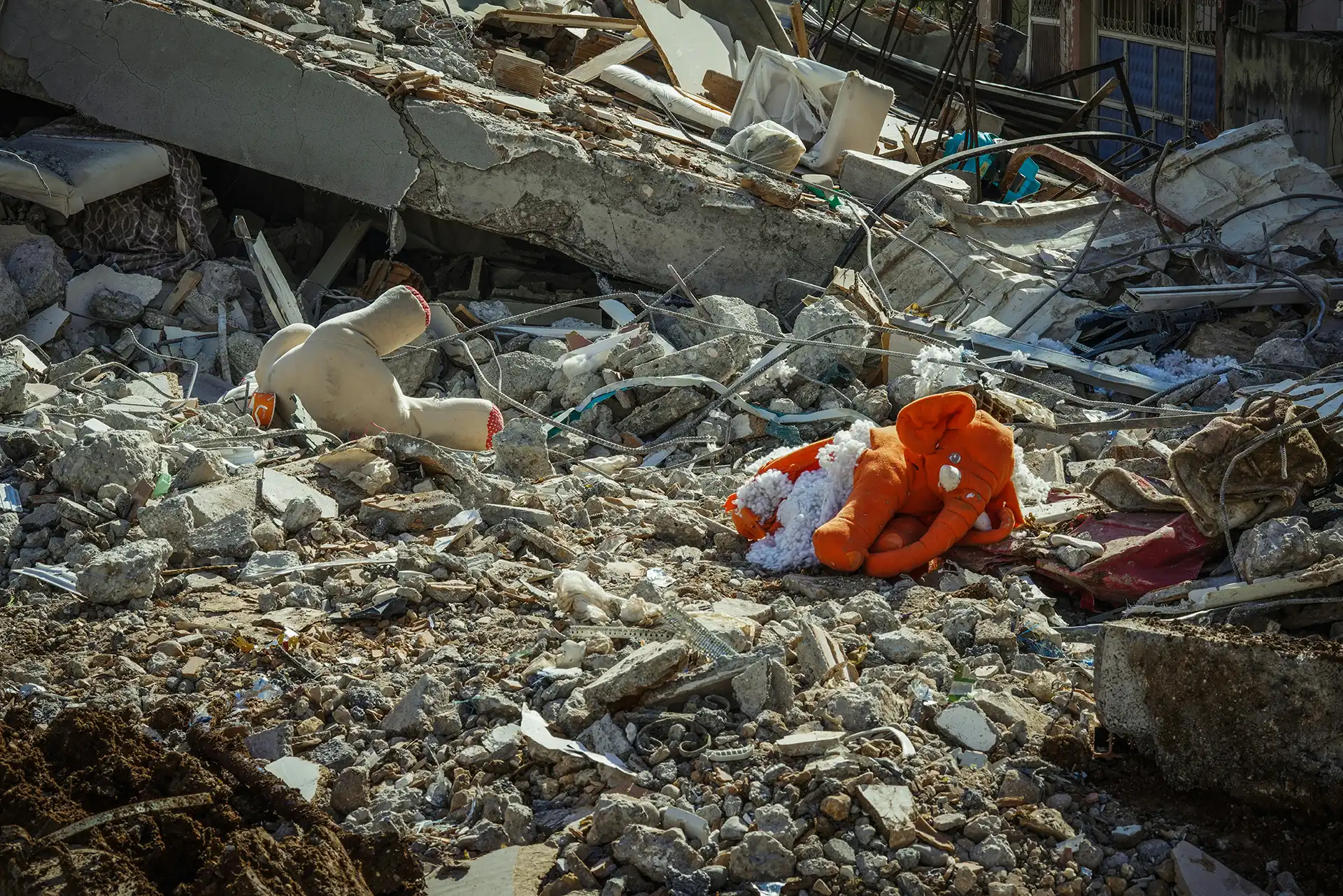 Rubble from an earthquake in Myanmar with stuffed animals laying on top.